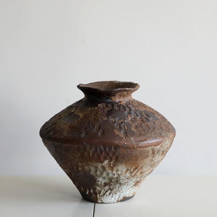 a brown vase sitting on top of a white table