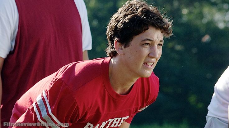 a young man holding a frisbee on top of a field