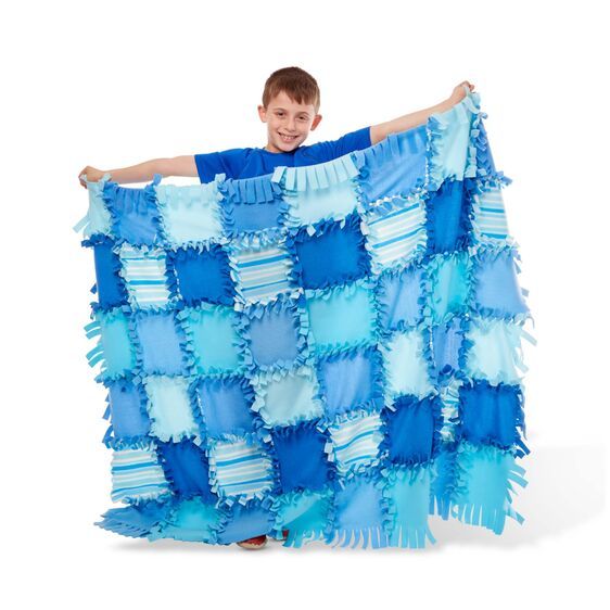 a young boy holding up a blue and white blanket with ruffles on it