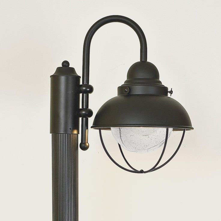 an outdoor light with a black pole and white glass ball on the top, against a white wall