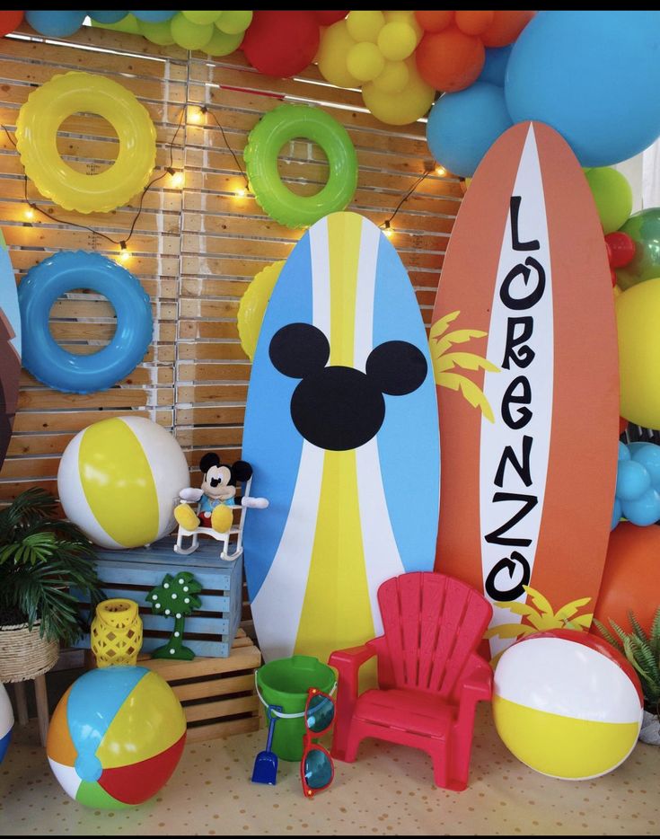 an assortment of beach themed items displayed in front of a wall with balloons and decorations