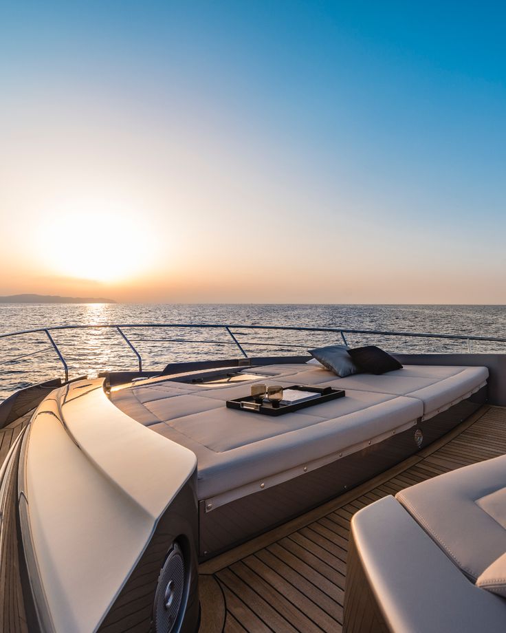 the sun is setting over the ocean on a boat with chaise lounges around it