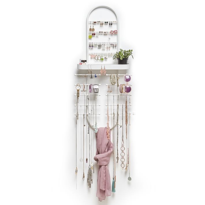 a white wall mounted jewelry rack with lots of necklaces hanging from it's sides