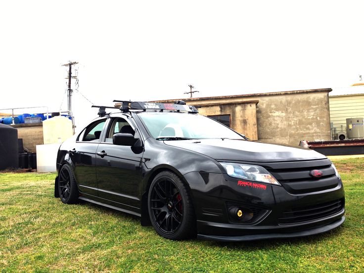 a black car parked on top of a lush green field