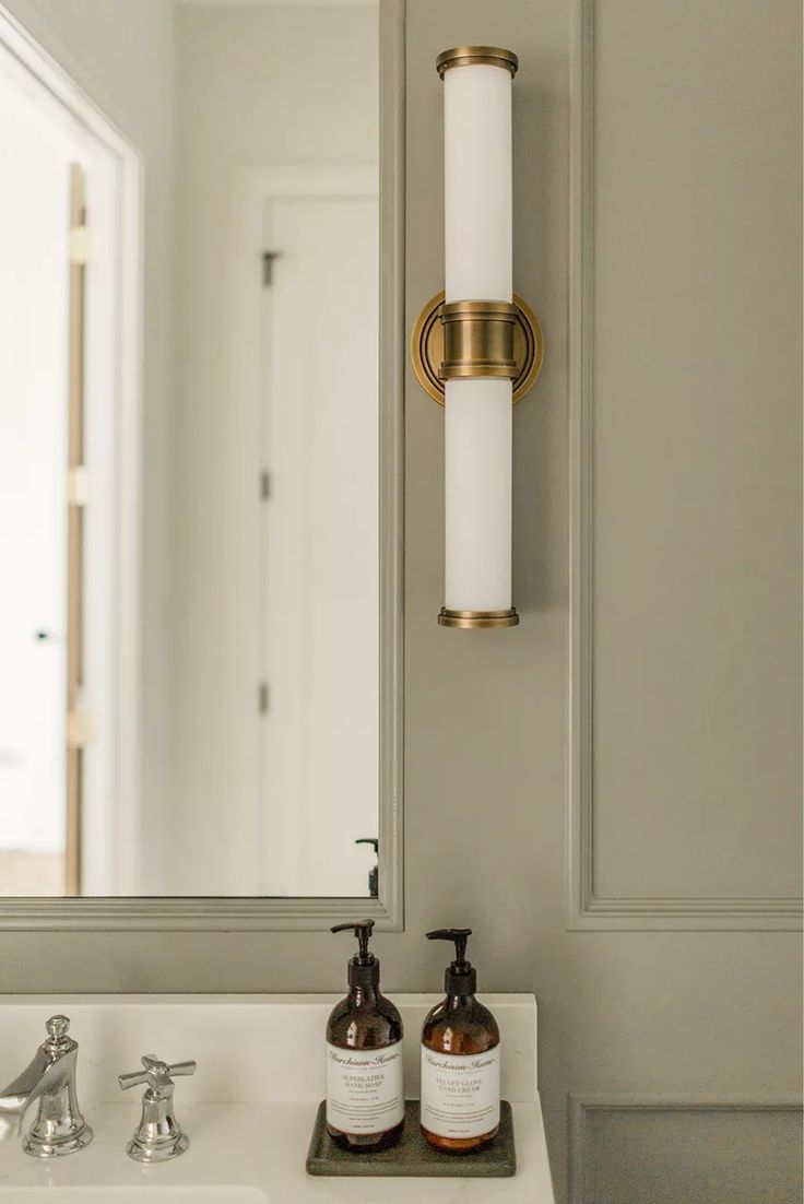 a white sink sitting under a bathroom mirror next to a wall mounted faucet