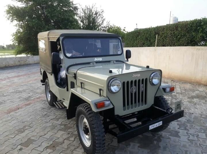 an old jeep is parked on the cobblestone road