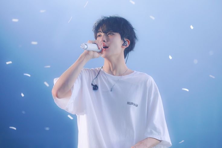 a male in a white t - shirt is drinking from a water bottle and confetti flies around him