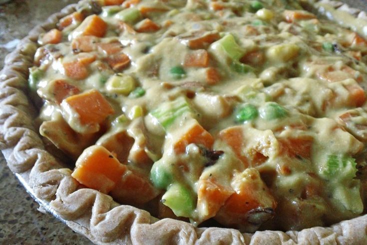 a pie with carrots, celery and other toppings in it on a table