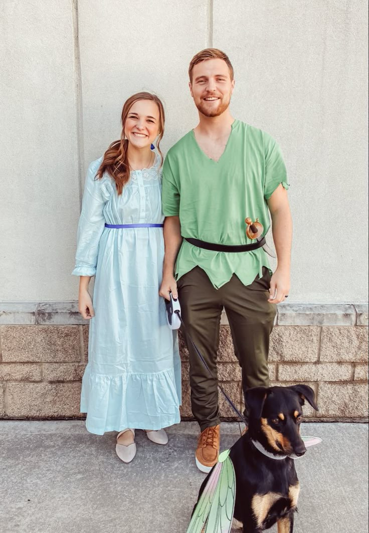 a man and woman dressed up as tinkerbells with a dog on a leash