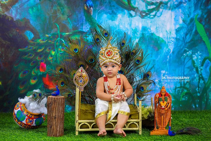 a baby sitting on a chair in front of peacocks and other decorative items, wearing a headdress