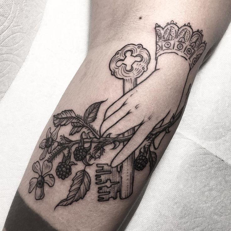 a tattoo with a hand holding a key and flowers on the arm that says love