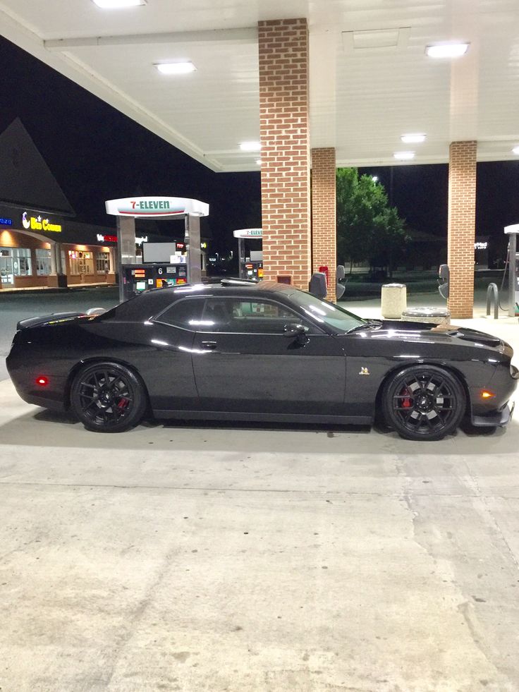 a black sports car parked in front of a gas station with no one around it