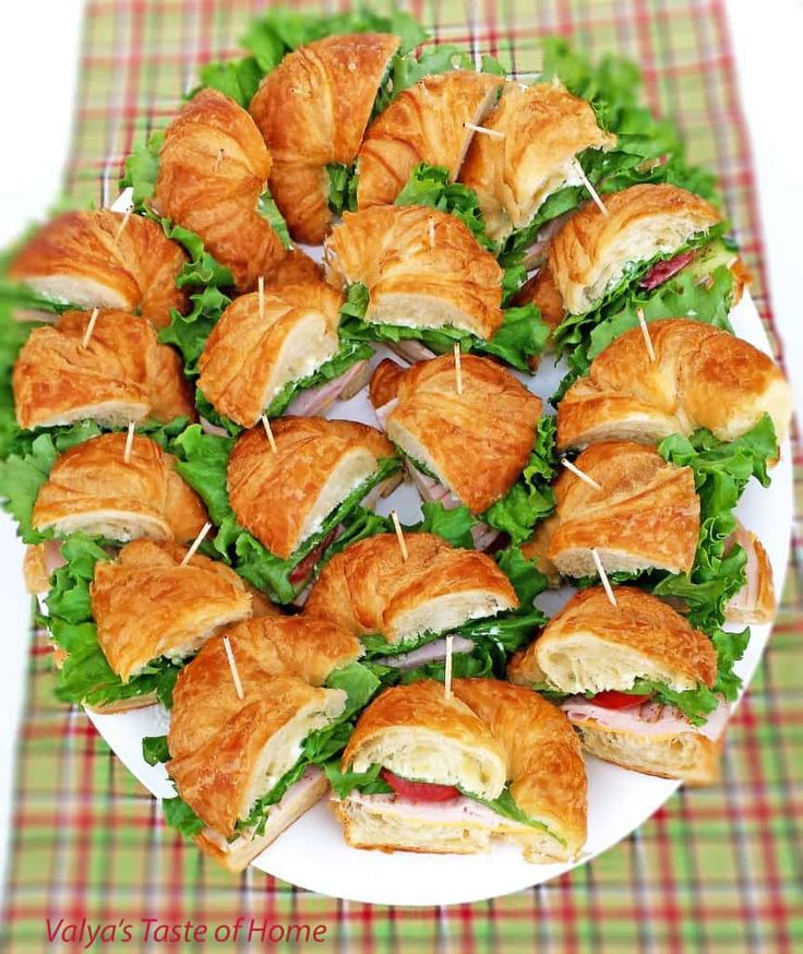 a white plate topped with sandwiches and croissants on top of a table