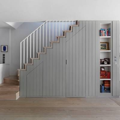 an open living room with stairs leading up to the second floor and bookshelves