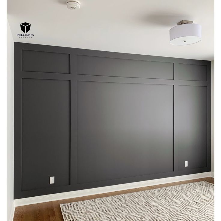 an empty room with dark gray walls and white rugs on the hardwood flooring