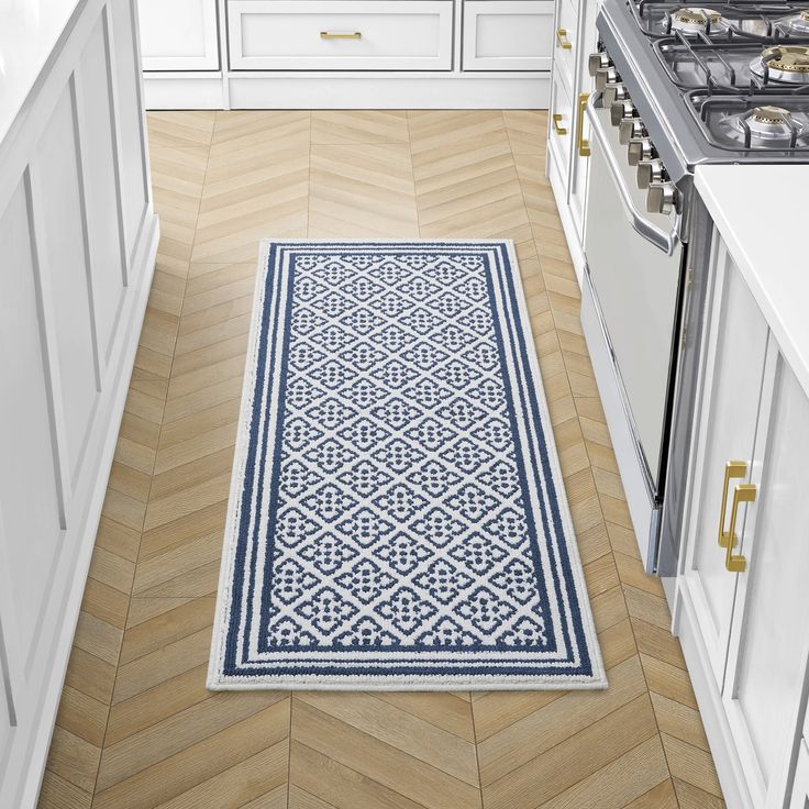 a blue and white rug in the middle of a kitchen with an oven, dishwasher and stove