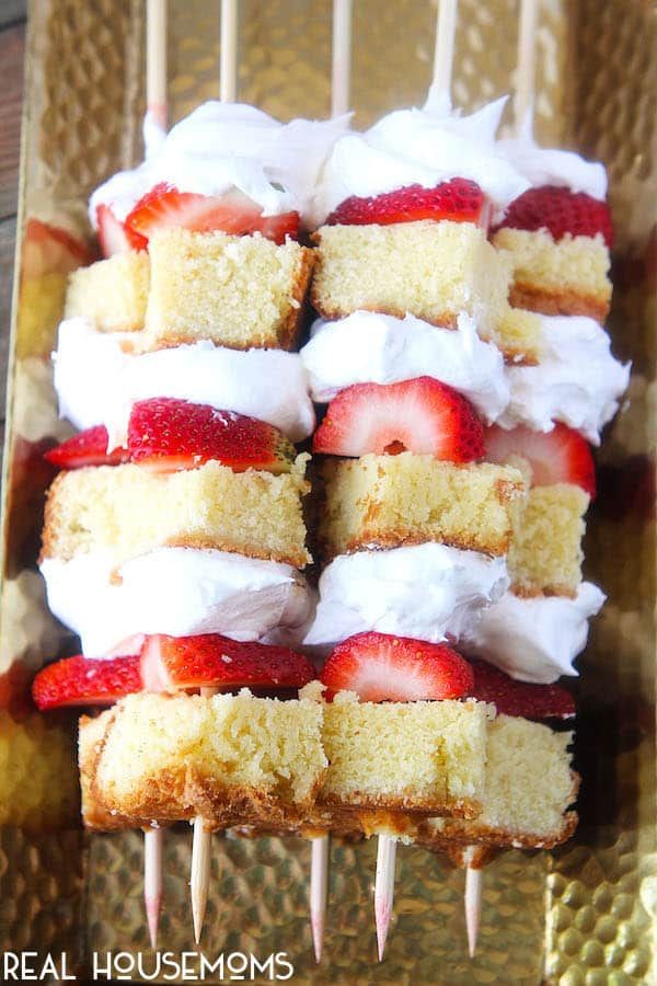 strawberry shortcakes with white frosting and strawberries on top are arranged on a gold platter