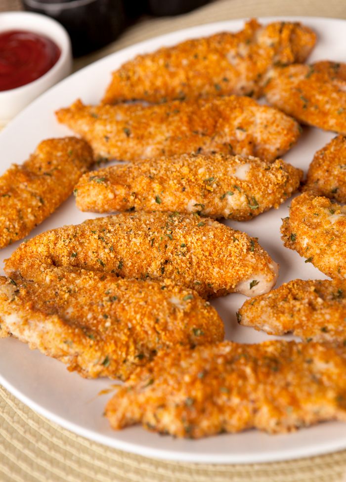 fried chicken pieces on a plate with ketchup and sauces in the background