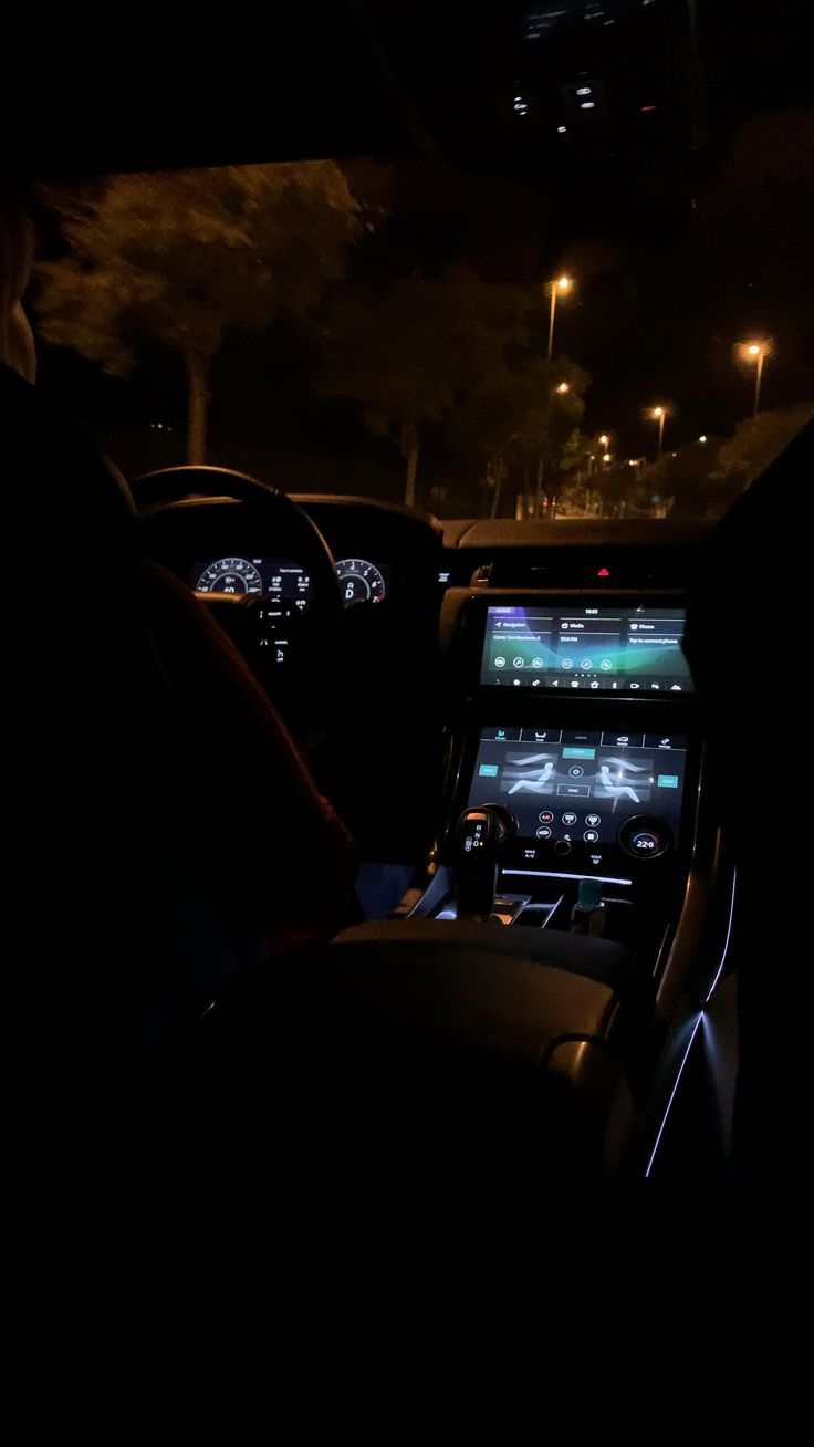 the interior of a car at night with its lights on and dashboard illuminated by streetlights