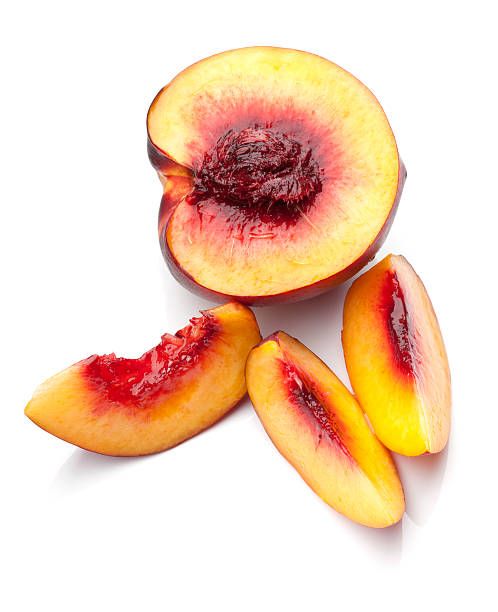 sliced peaches on a white background with one cut in half