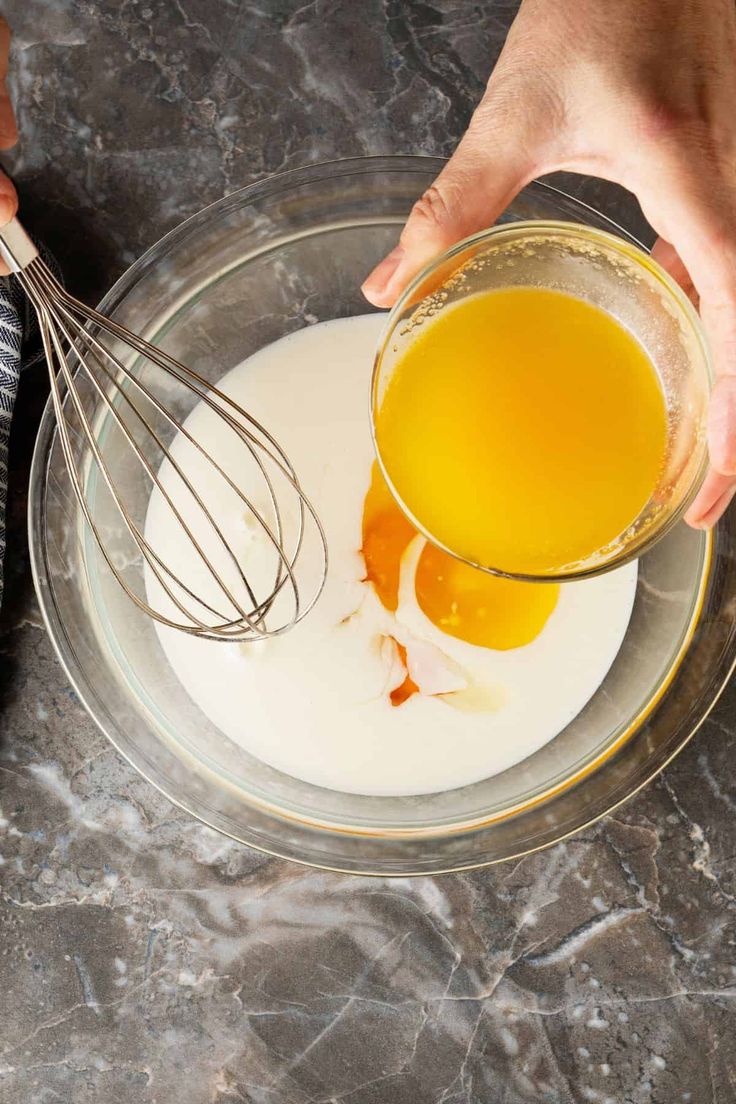 two hands whisk eggs into a bowl