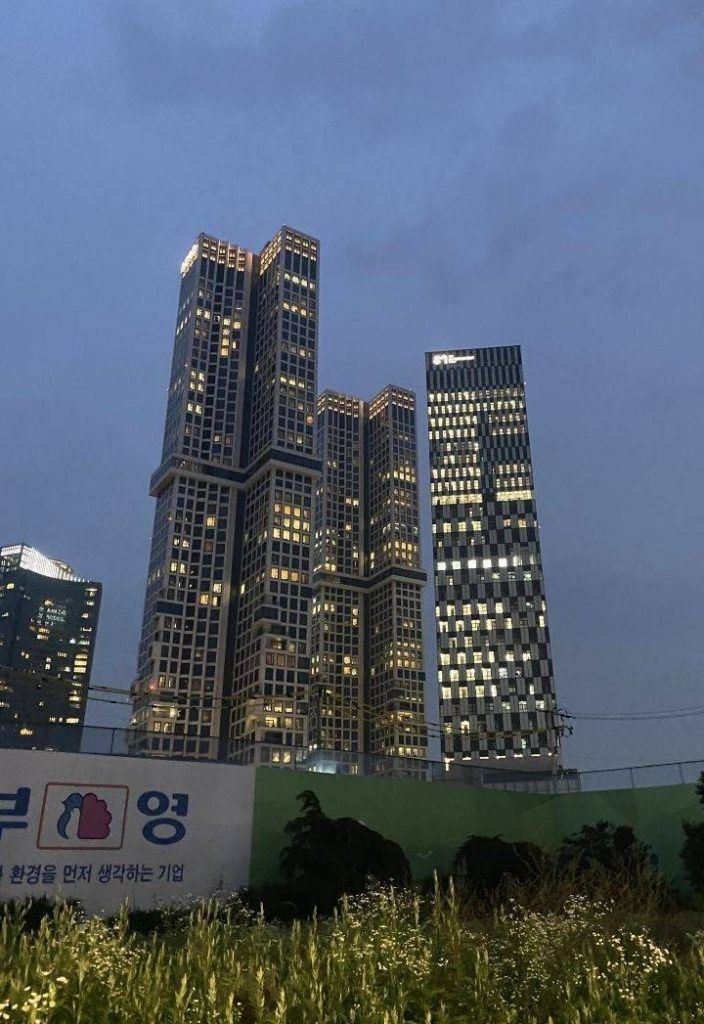 the skyscrapers are lit up at night in front of green grass and blue sky