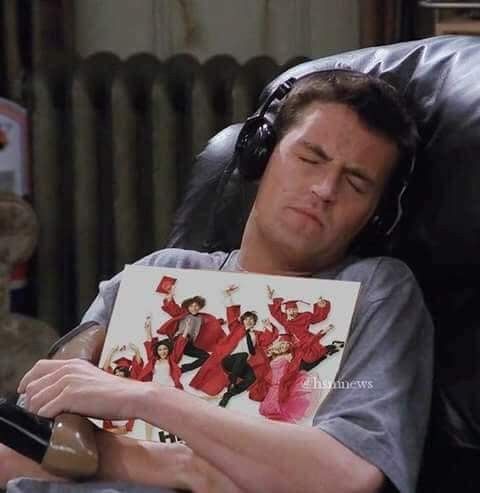 a man sitting in a chair while holding a book with his face covered by headphones