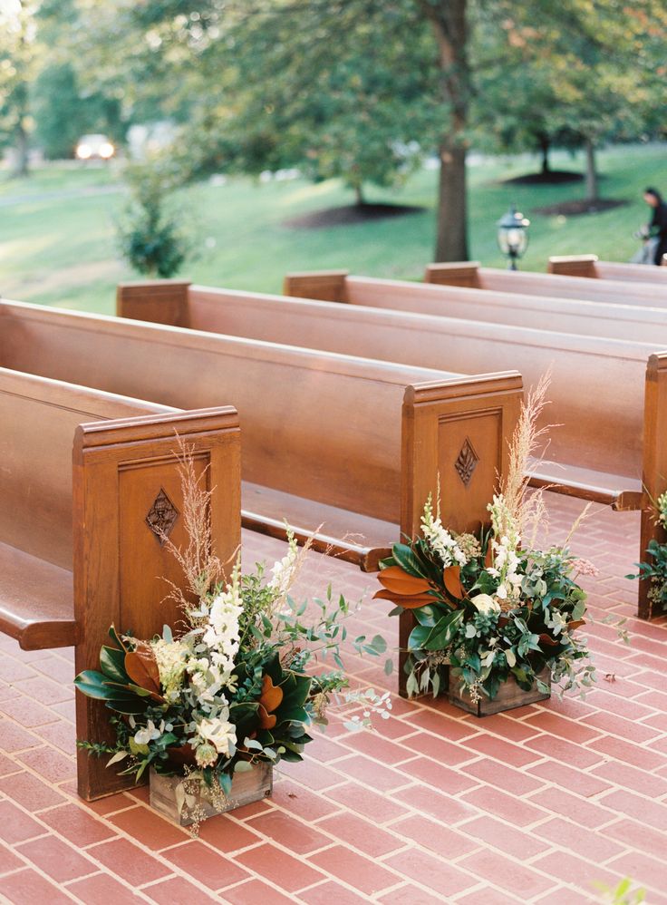 three wooden benches with flowers in them on a brick floor next to grass and trees