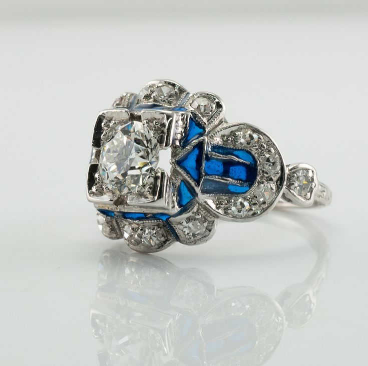 This vintage ring is crafted in solid 14K White Gold (carefully tested and guaranteed). The center Old European cut diamond is .75 carat of VS1 clarity and G color! It is accented with 18 mine cut diamonds of SI1-I1 clarity and H color totaling .38 carat. The blue enamel is in mint condition. The top of the ring measures 13mm top to bottom. The setting elevates 6mm high above finger. Size 4.5 (sizable). The ring weighs 4.2 grams. Great vintage condition. T5183455 Blue Diamond Enamel Ring Fine Jewelry, Blue Enamel Diamond Ring Fine Jewelry, Blue Diamond Enamel Ring For Formal Occasions, Formal Blue Enamel Diamond Ring, Formal Round Enamel Diamond Ring, Gia Certified Blue Art Deco Jewelry, Blue Art Deco Jewelry Gia Certified, Antique Blue Diamond Ring For Anniversary, Diamond Enamel Ring With Brilliant Cut For Anniversary