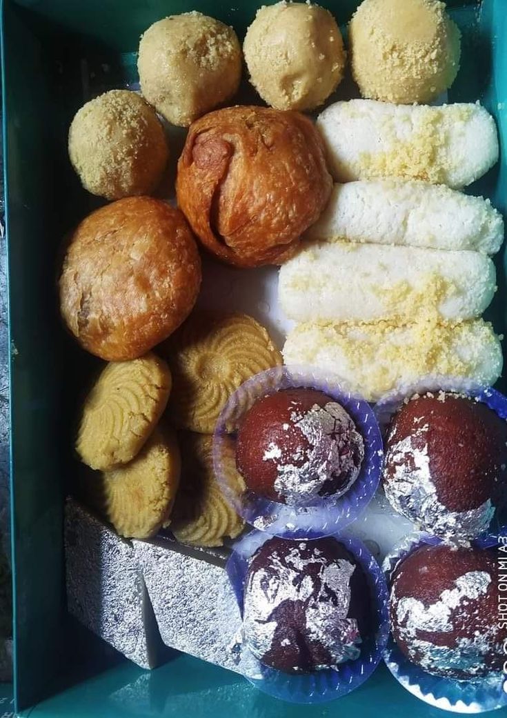 there are many different types of pastries in this blue box with white powdered sugar on them