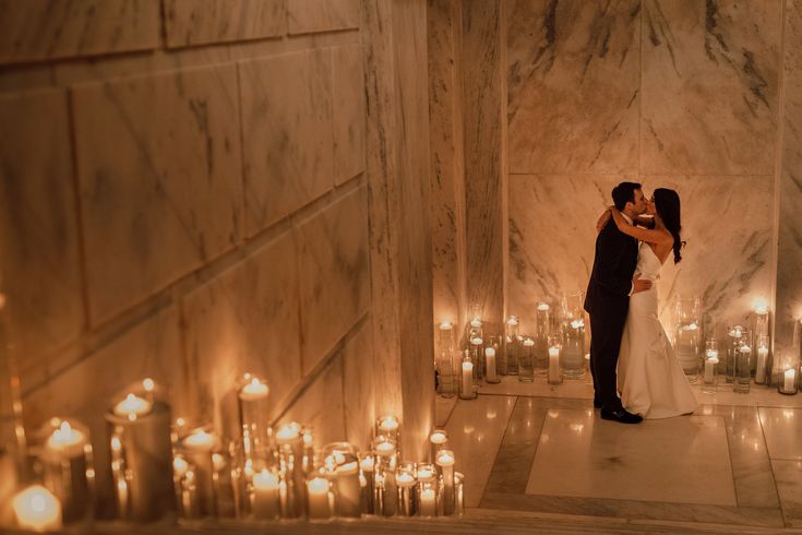 a bride and groom kissing in front of candles