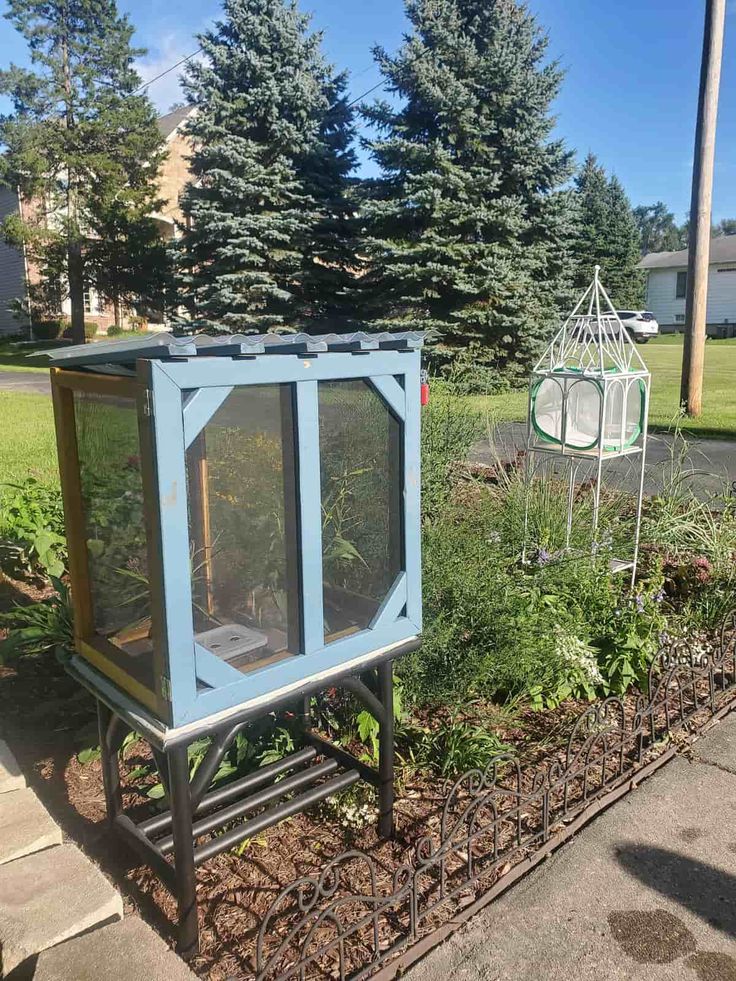 a small blue box sitting in the middle of a garden