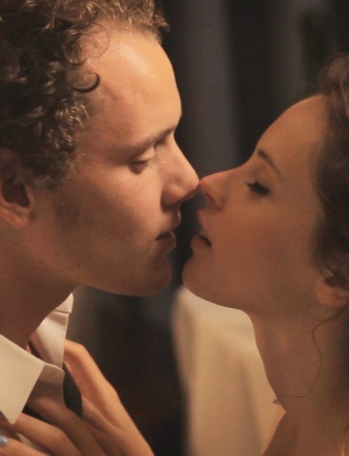 a man and woman kissing each other while they are dressed in formal wear, with one being kissed by the other