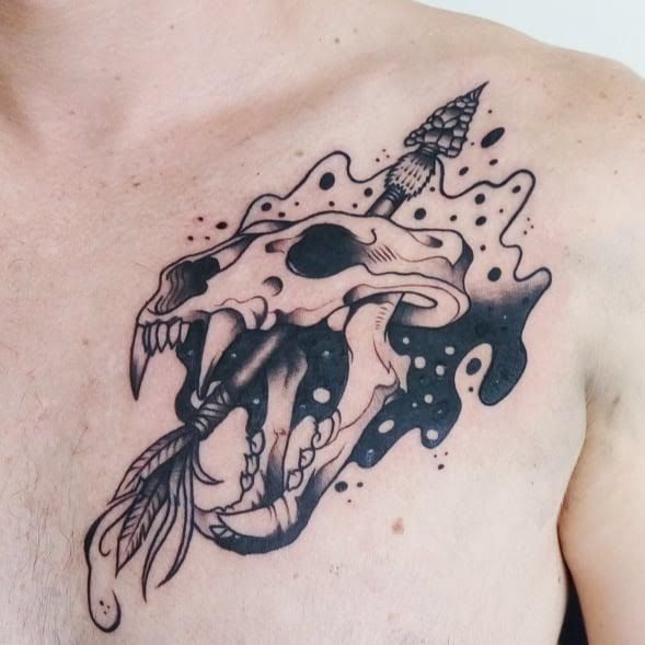 a man's chest with a black and white tattoo design on it, including an animal skull