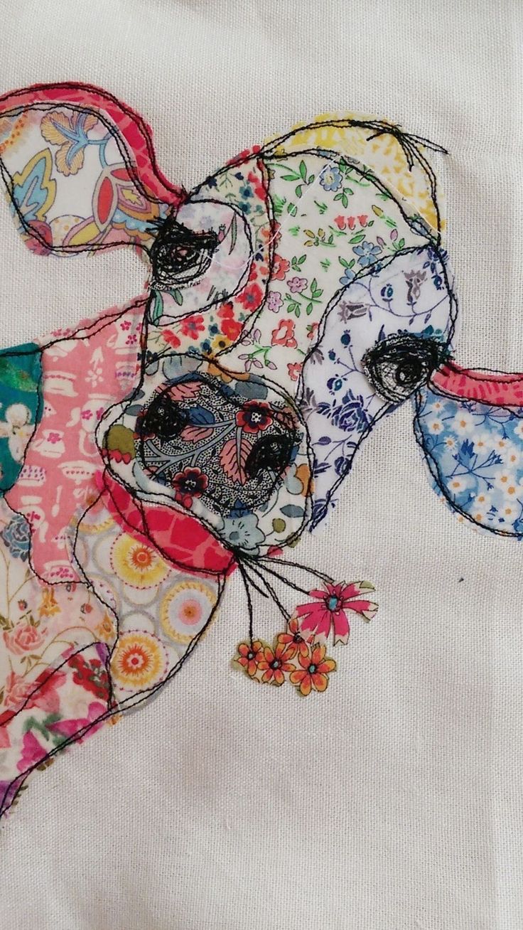 a close up of a colorful cow on a white cloth with flowers and butterflies around it