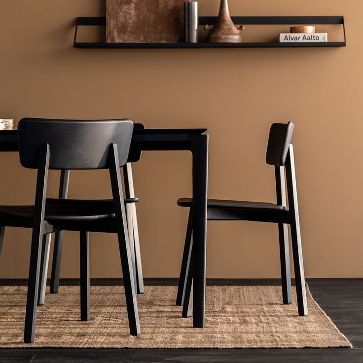 two black chairs sitting next to each other on top of a rug in front of a brown wall