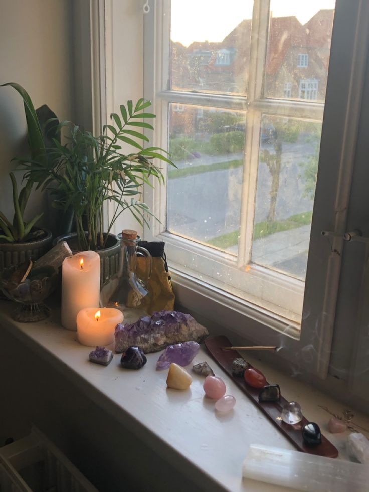 a window sill with candles, rocks and other items sitting on the windowsill