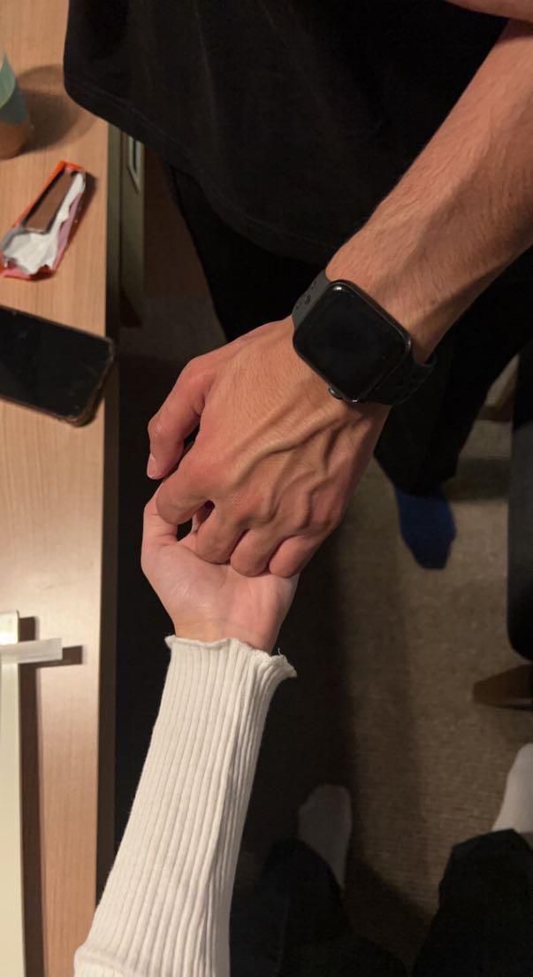 two people holding hands while sitting at a table