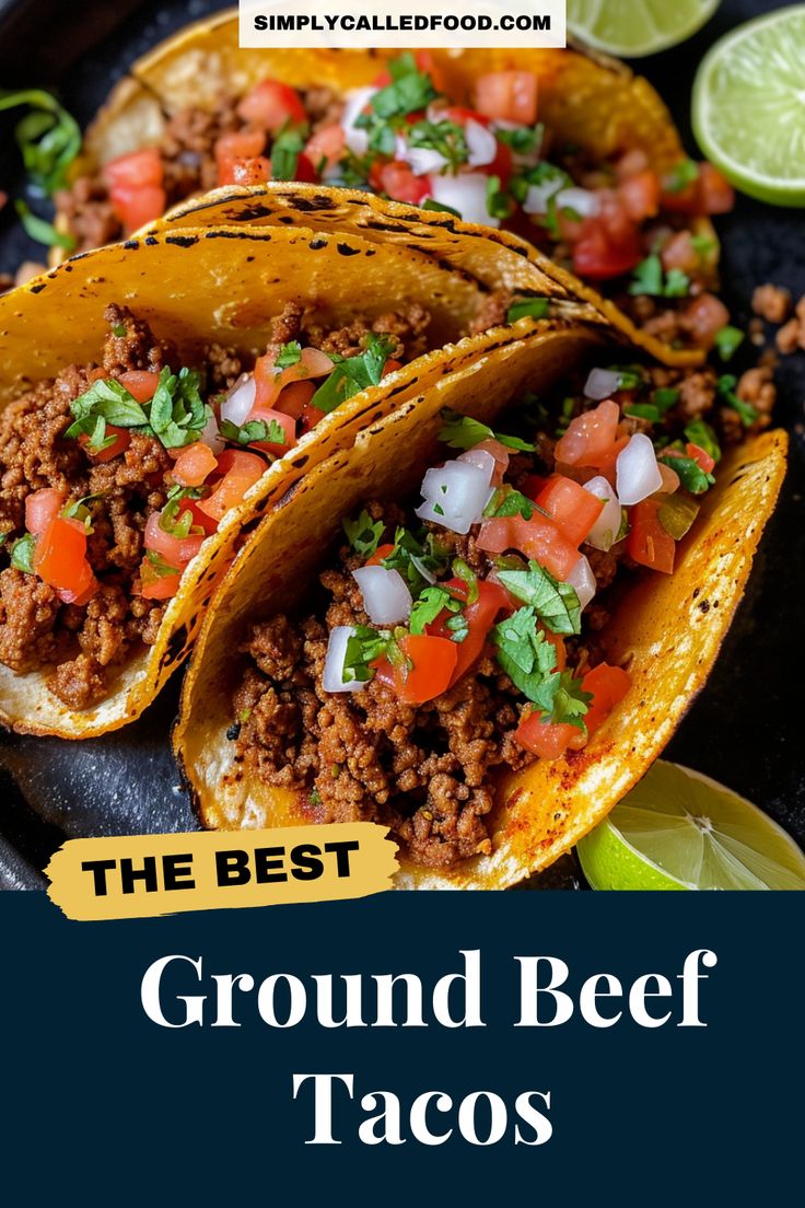 three ground beef tacos on a black plate with limes and cilantro