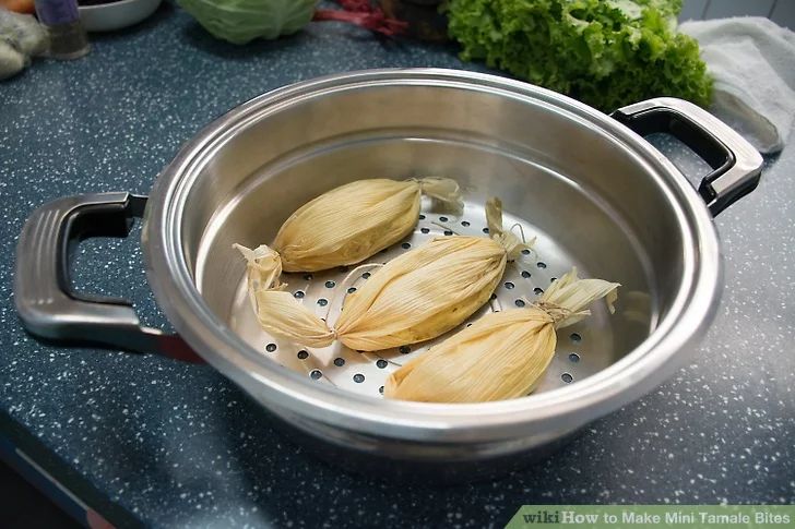 three pieces of garlic are in a pot on the stove top, with water running through it