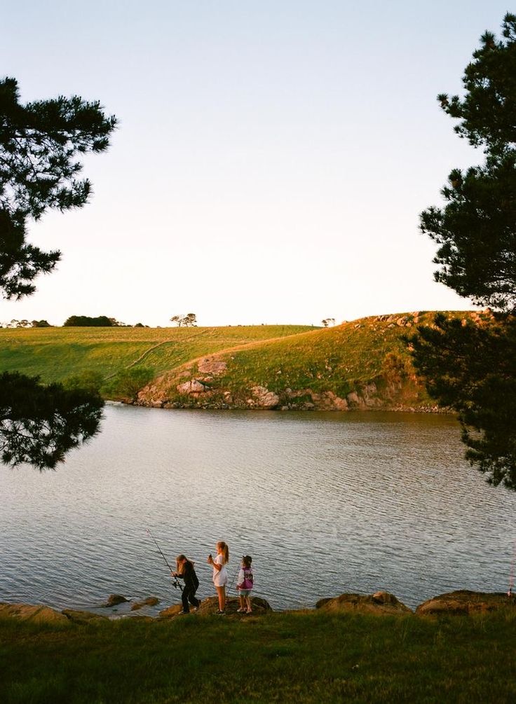 three children fishing on the shore of a lake