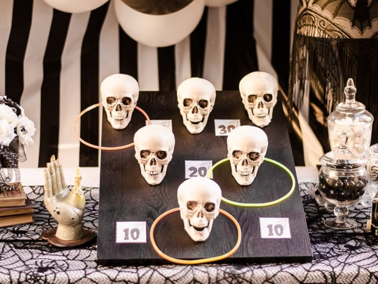 a table topped with lots of fake skulls on top of a black and white table cloth