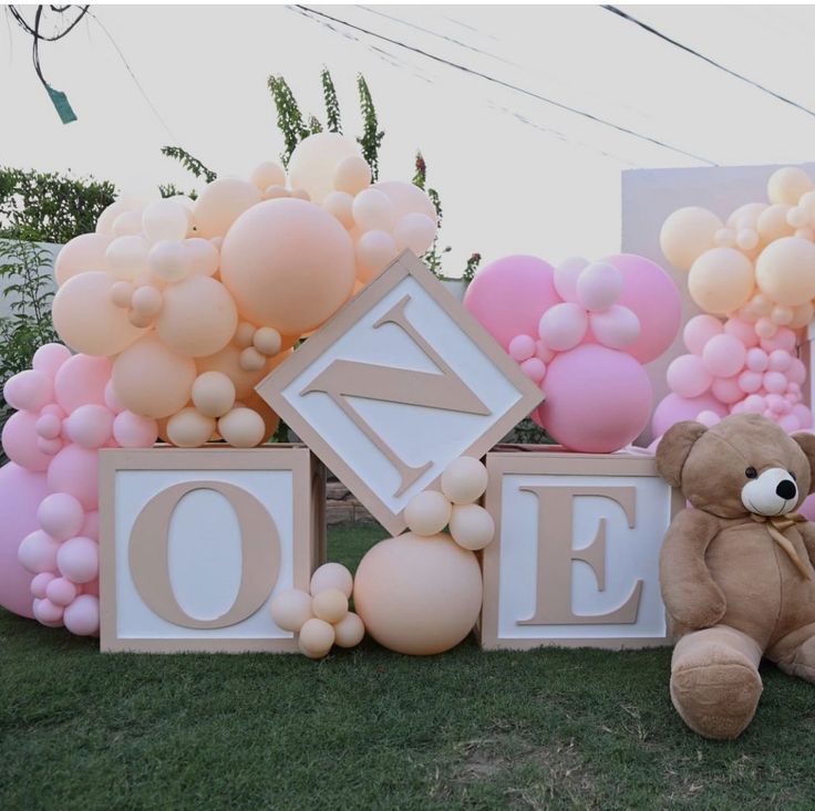 a teddy bear is sitting in front of balloons and blocks that spell out the word love