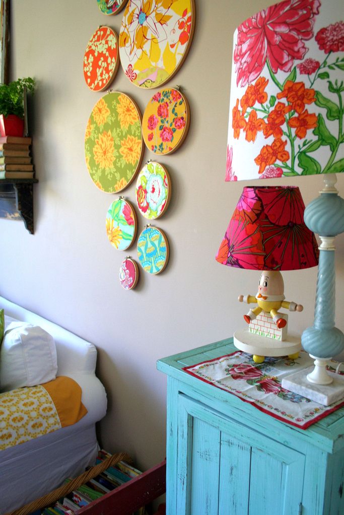 a room with a bed, lamp and colorful wall decorations on the wall above it