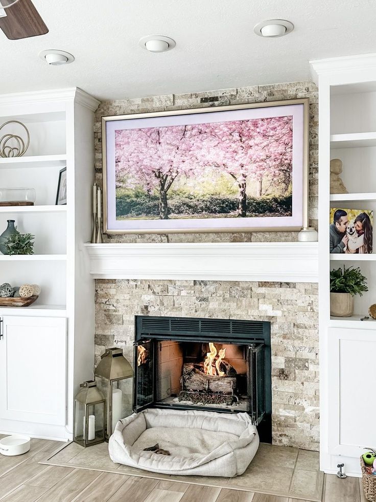 a living room with a fire place and bookshelves on the wall above it