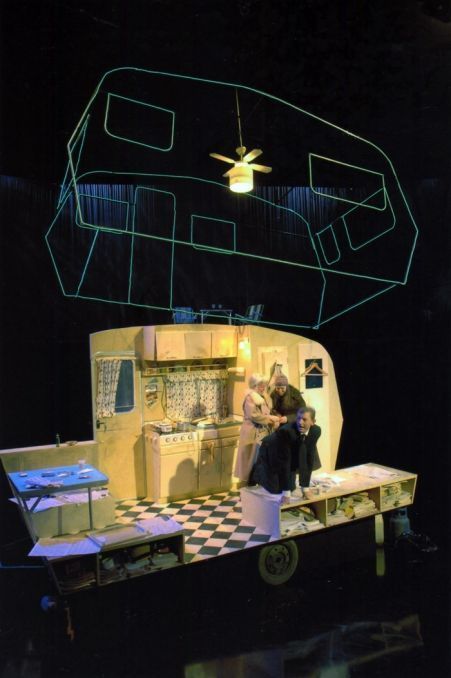 two people standing on top of a table in front of a fake kitchen and stove