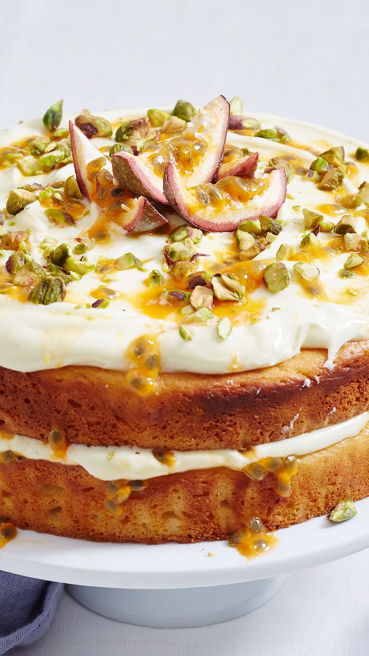 a cake with white frosting and fruit toppings on top sits on a plate