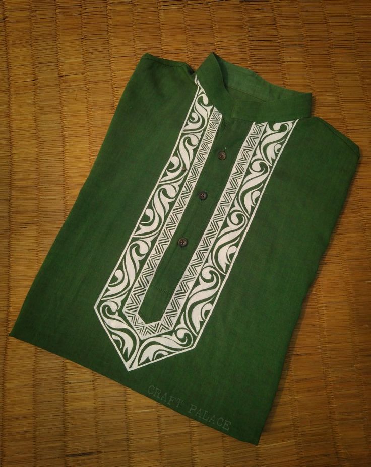 a green shirt with white designs on the front and back, sitting on a bamboo floor