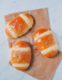 three hot dogs wrapped in bread sitting on top of a piece of paper