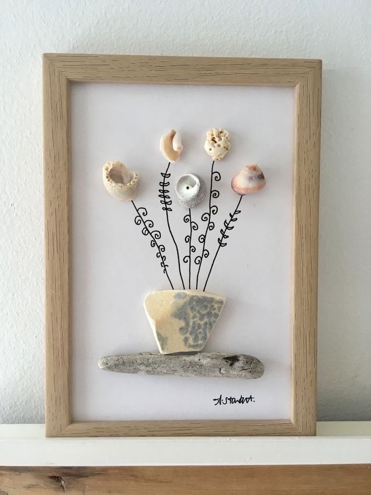 a wooden frame with shells and flowers in it on top of a shelf next to a white wall